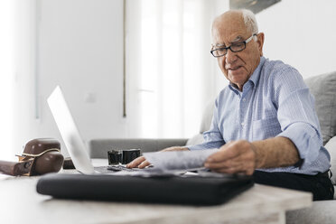 Ein älterer Mann arbeitet mit einem Computer und seinen alten Fotoapparaten und alten Fotos - JRFF01669