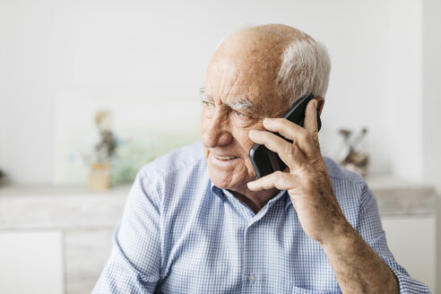 Glücklicher älterer Mann, der zu Hause sein Smartphone benutzt - JRFF01679