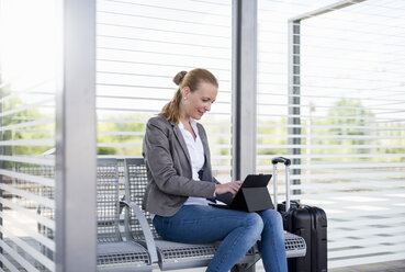 Smiling mature businesswoman using tablet while waiting at platform - DIGF04473