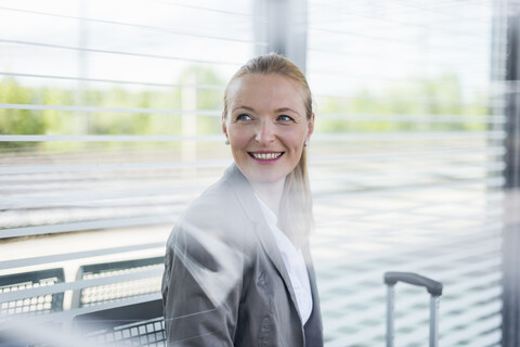 Porträt einer lächelnden reifen Geschäftsfrau, die am Bahnsteig wartet, lizenzfreies Stockfoto