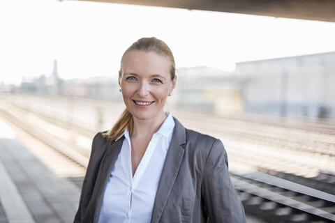 Porträt einer lächelnden Geschäftsfrau am Bahnsteig, lizenzfreies Stockfoto