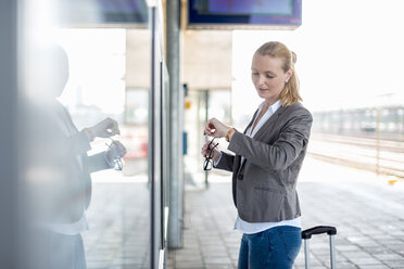 Mature businesswoman standing at platform checking the ime - DIGF04483