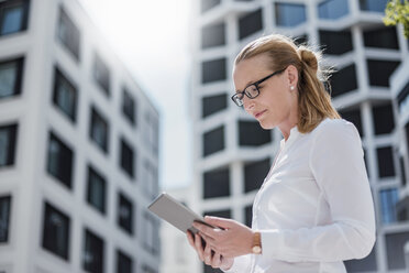 Portrait of businesswoman using tablet outdoors - DIGF04495