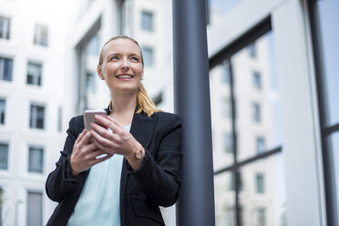 Portrait of smiling businesswoman with cell phone waiting - DIGF04498