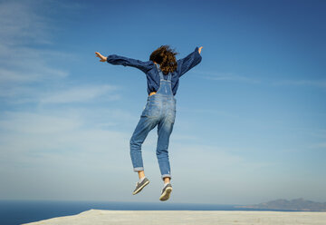 Girl in midair, sea and sky in background, Oía, Santorini, Kikladhes, Greece - ISF02624