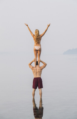 Junges Paar am Strand, Frau steht auf den Schultern des Mannes, Rückansicht, lizenzfreies Stockfoto