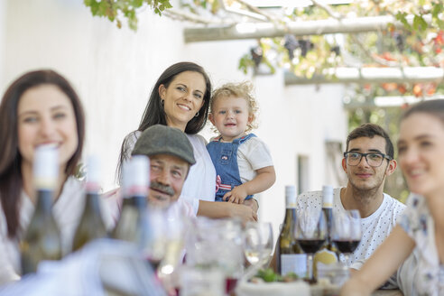 Familie beim Mittagessen im Freien unter einem Weinrebenspalier - ISF02767