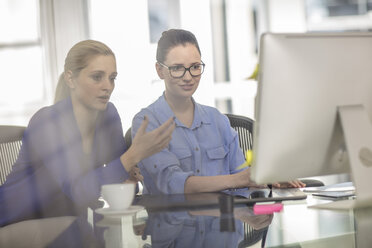 Two young female office workers having meeting at desk - ISF02778