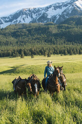 Teenager-Mädchen führt vier Pferde durch schneebedeckten Berg, Enterprise, Oregon, Vereinigte Staaten, Nordamerika - ISF02790