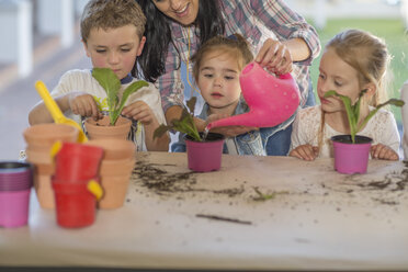 Mid adult woman helping young children with gardening activity - ISF02795