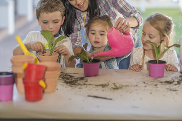 Mittlere erwachsene Frau hilft kleinen Kindern bei der Gartenarbeit - ISF02795