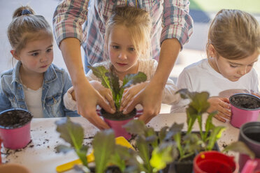 Mittlere erwachsene Frau hilft kleinen Kindern bei der Gartenarbeit - ISF02797