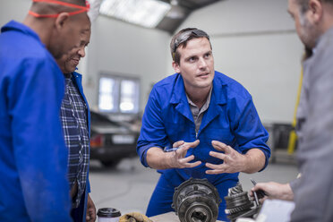 Automechanikerteam bei der Besprechung von Autoteilen in einer Werkstatt - ISF02844