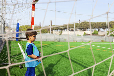 Little boy standing at goal on football ground - VABF01612