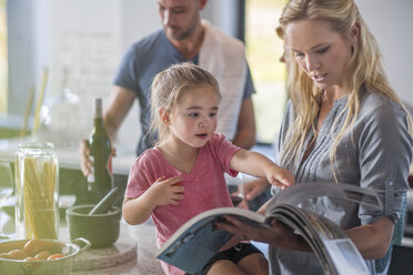 Familie in der Küche, Mutter und Tochter blättern in einem Buch - ISF02891