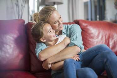 Mutter und Tochter auf dem Sofa kuschelnd und lächelnd - ISF02926