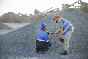 Two quarry workers in quarry, checking aggregate - ISF02934