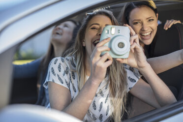 Junge Frau im Auto mit zwei Freunden, die aus dem Autofenster fotografieren - ISF02942