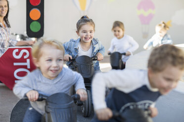 Jungen und Mädchen in der Vorschule, die Motorräder im Garten schieben - ISF02946