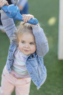 Girl at preschool, holding playground rope swing in garden - ISF02949