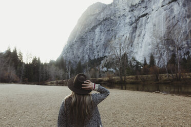 Rear view of woman holding hat looking out at mountain, Yosemite National Park, California, USA - ISF02966