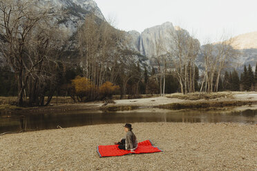 Frau auf roter Decke sitzend mit Blick auf die Landschaft, Yosemite National Park, Kalifornien, USA - ISF02967