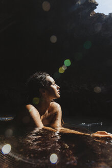 Woman in water filled cave eyes closed looking away, Oahu, Hawaii, USA - ISF02984