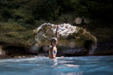 Frau in wassergefüllter Höhle schaut in die Kamera, Oahu, Hawaii, USA - ISF02985