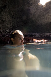 Frau in wassergefüllter Höhle schaut weg, Oahu, Hawaii, USA - ISF02986