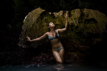 Frau in wassergefüllter Höhle in Badekleidung schaut nach oben, Oahu, Hawaii, USA - ISF02988