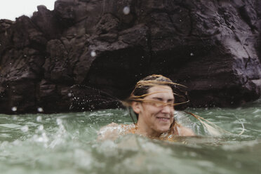 Woman in sea shaking head, splashing, Oahu, Hawaii, USA - ISF02996