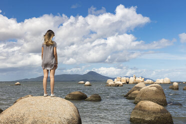 Rear view of teenage girl on rock looking at view of sea - ISF03032