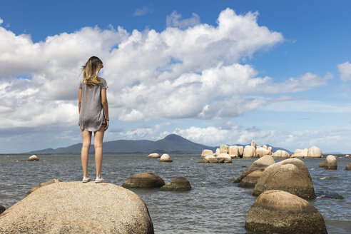 Rückansicht eines jugendlichen Mädchens auf einem Felsen mit Blick auf das Meer - ISF03032