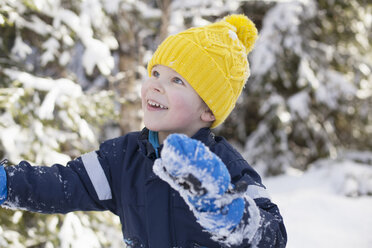 Junge mit gelber Strickmütze blickt in den verschneiten Wald - ISF03081