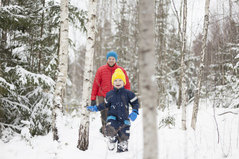Mann und Sohn spazieren im verschneiten Wald - ISF03083