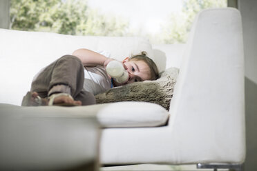 Babymädchen trinkt aus Milchflasche auf Sofa - ISF03106