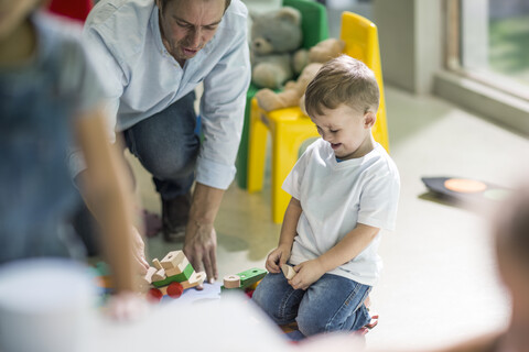Lehrer und Junge spielen mit Spielzeugeisenbahn, lizenzfreies Stockfoto