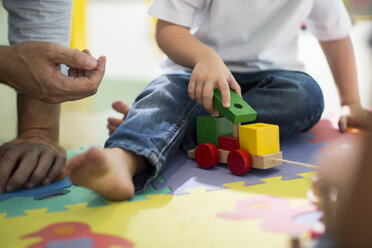 Lehrer und Junge spielen mit Spielzeugeisenbahn - ISF03109