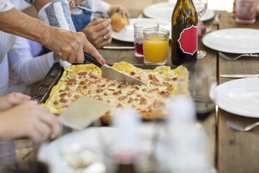Frau schneidet Pizza am Mittagstisch auf - ISF03114