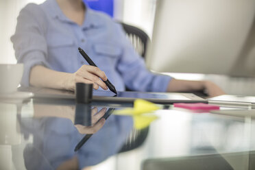 Mittelteil einer jungen Büroangestellten am Schreibtisch mit digitalem Stift - ISF03154