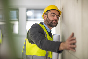 Man holding blueprint surveying wall - ISF03176