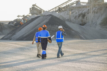 Three quarry workers, walking across quarry, rear view - ISF03183