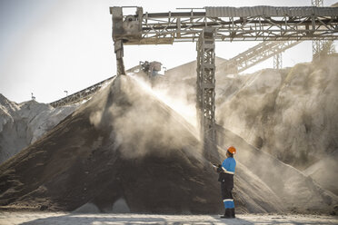 Quarry worker standing beside pile of aggregate in quarry - ISF03190