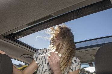 Junge Frau im Auto, die aus dem offenen Sonnendach schaut - ISF03202