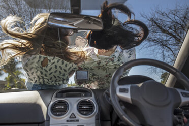 Zwei Frauen auf der Motorhaube eines Autos liegend, von innen gesehen - ISF03204