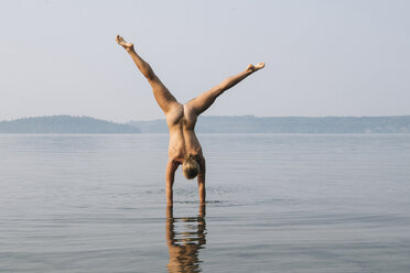 Rückansicht einer nackten Frau beim Handstand im Wasser - ISF03214