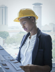 Woman in hard hat looking at building plans - ISF03216