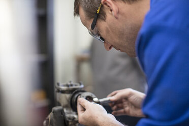 Männlicher Automechaniker bei der Arbeit in einer Reparaturwerkstatt - ISF03229