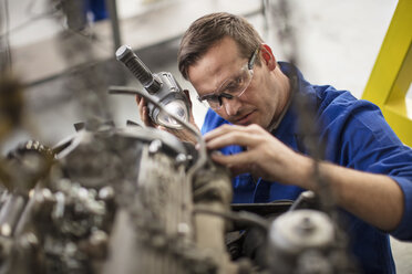 Car mechanic inspecting car part in repair garage - ISF03238