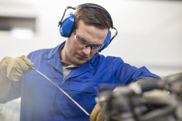 Automechaniker bei der Ölkontrolle in der Reparaturwerkstatt - ISF03239